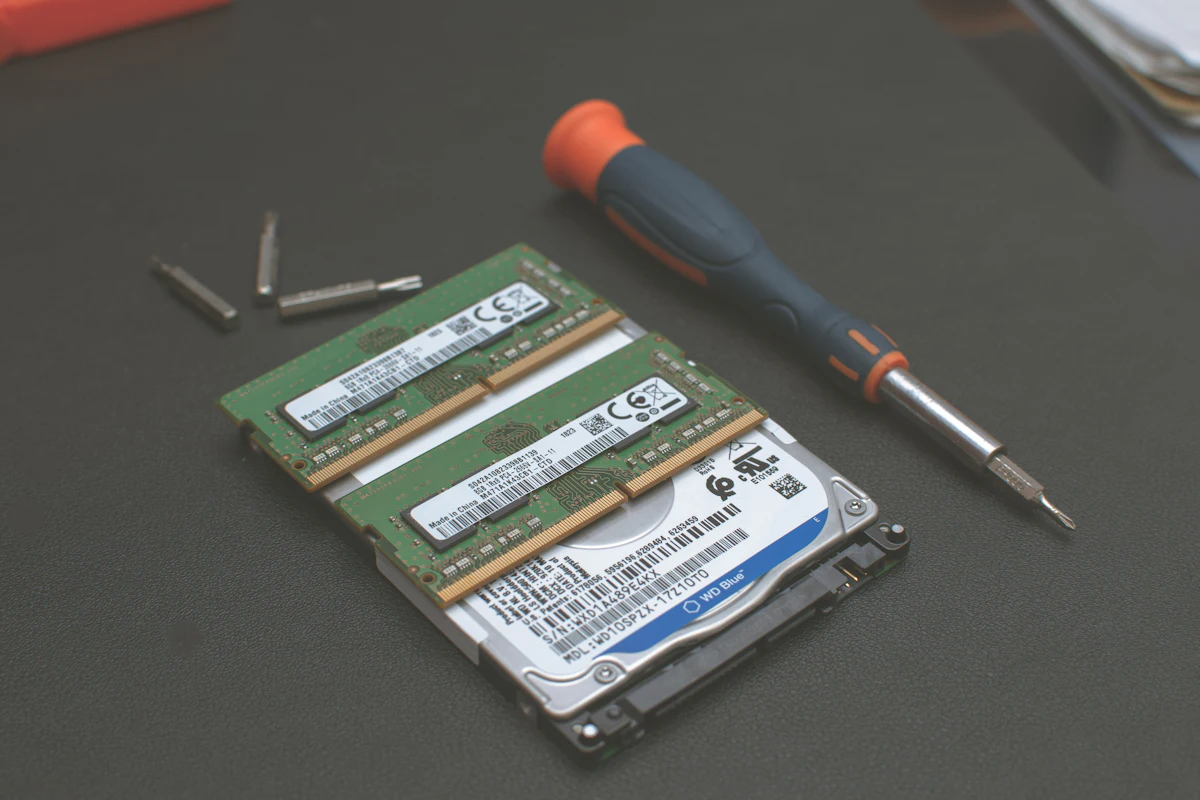 Disque dur 2,5 pouces de PC portable et deux barrettes de mémoire posés près d&rsquo;un tournevis et de ses embouts