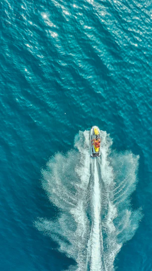 A vibrant jet ski cutting through turquoise waves under a bright Dar es Salaam sky.
