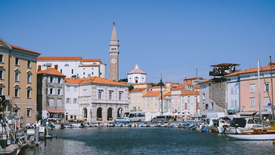 white and brown concrete building beside body of water during daytime in Tartini Square Slovenia