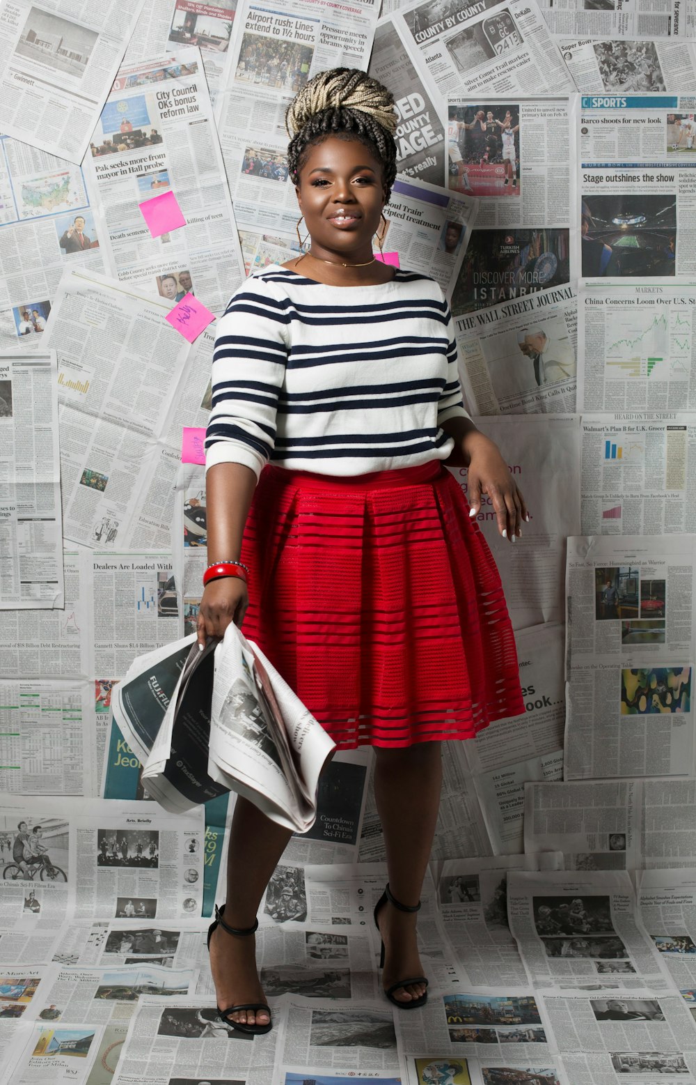 woman in white and black stripe shirt and red skirt standing