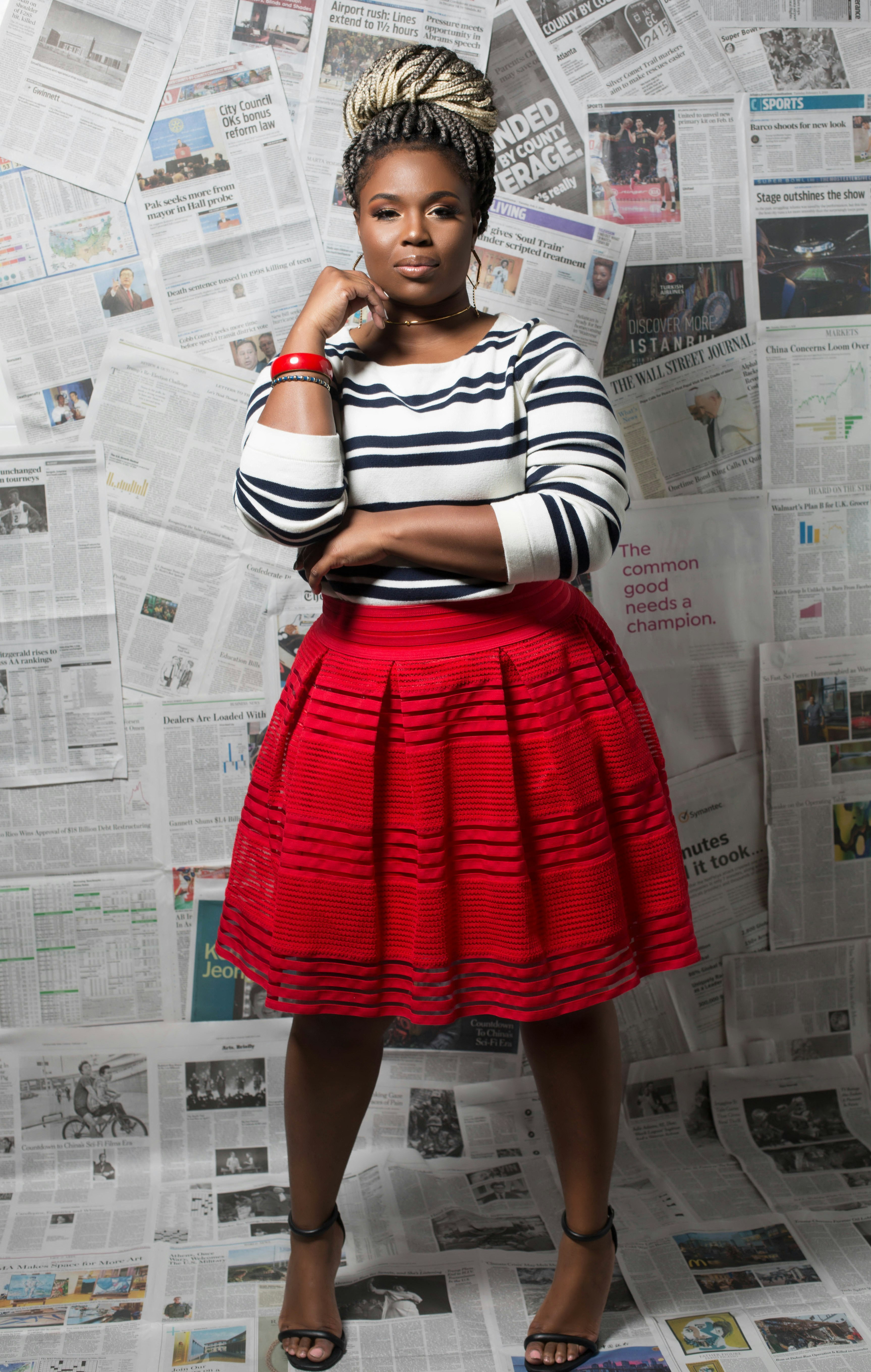 woman in black and white striped long sleeve shirt and red skirt standing beside white wall