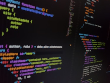 A close-up view of a computer screen displaying colorful lines of code. The code includes various programming elements such as functions, variables, and syntax highlighting. The text is slightly out of focus, emphasizing the depth of field and the dynamic nature of coding.