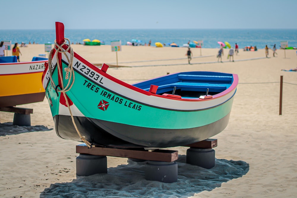 白、赤、青のボートが日中のビーチに浮かぶ