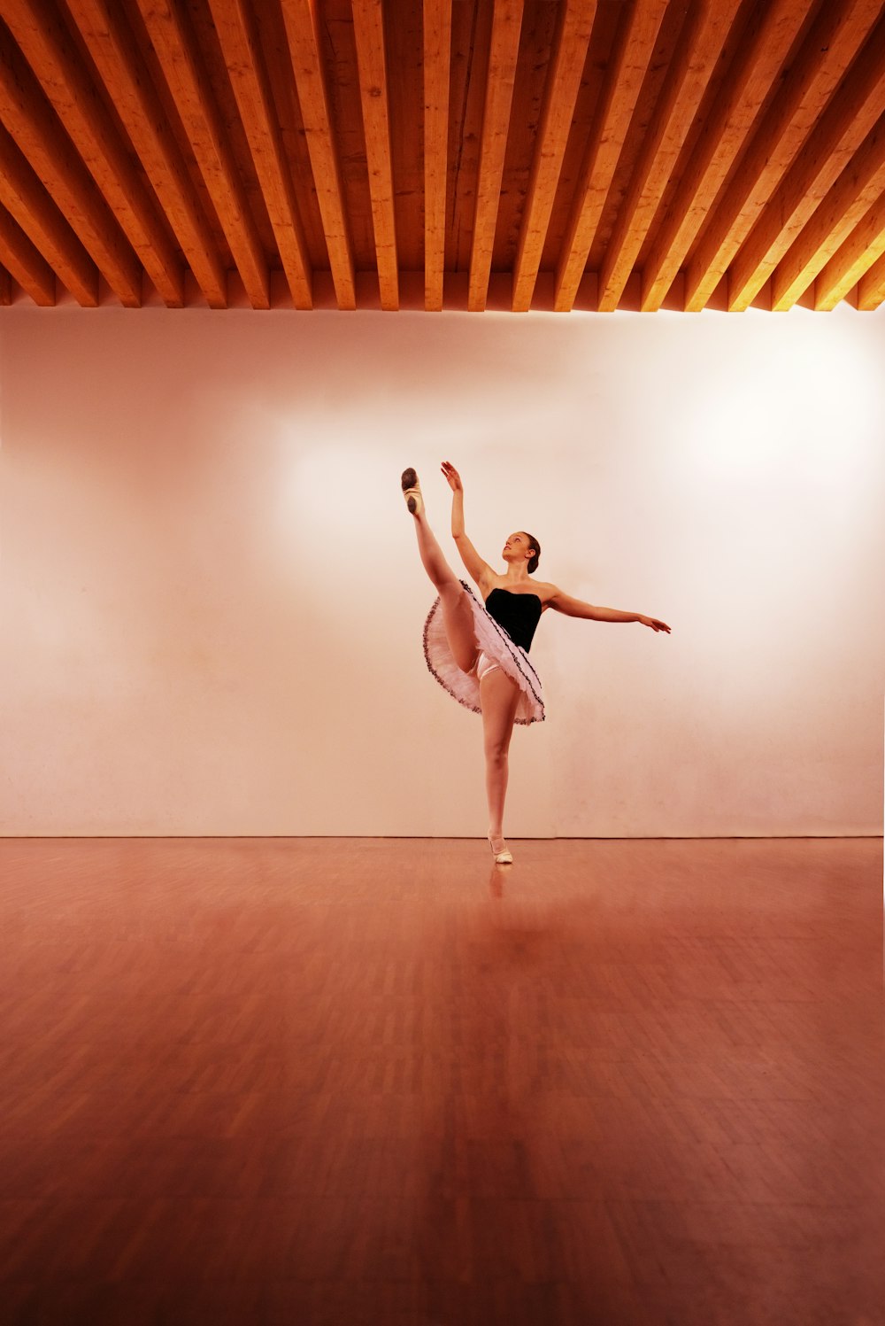 woman in black tank top and pink panty jumping on brown wooden floor