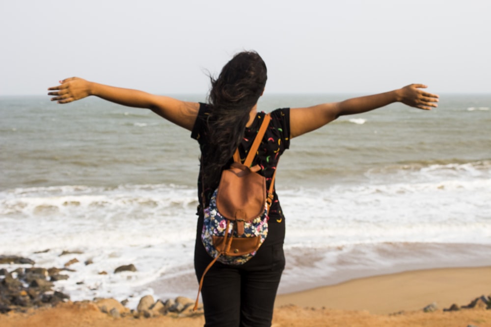 woman in black and orange floral bikini standing on beach during daytime