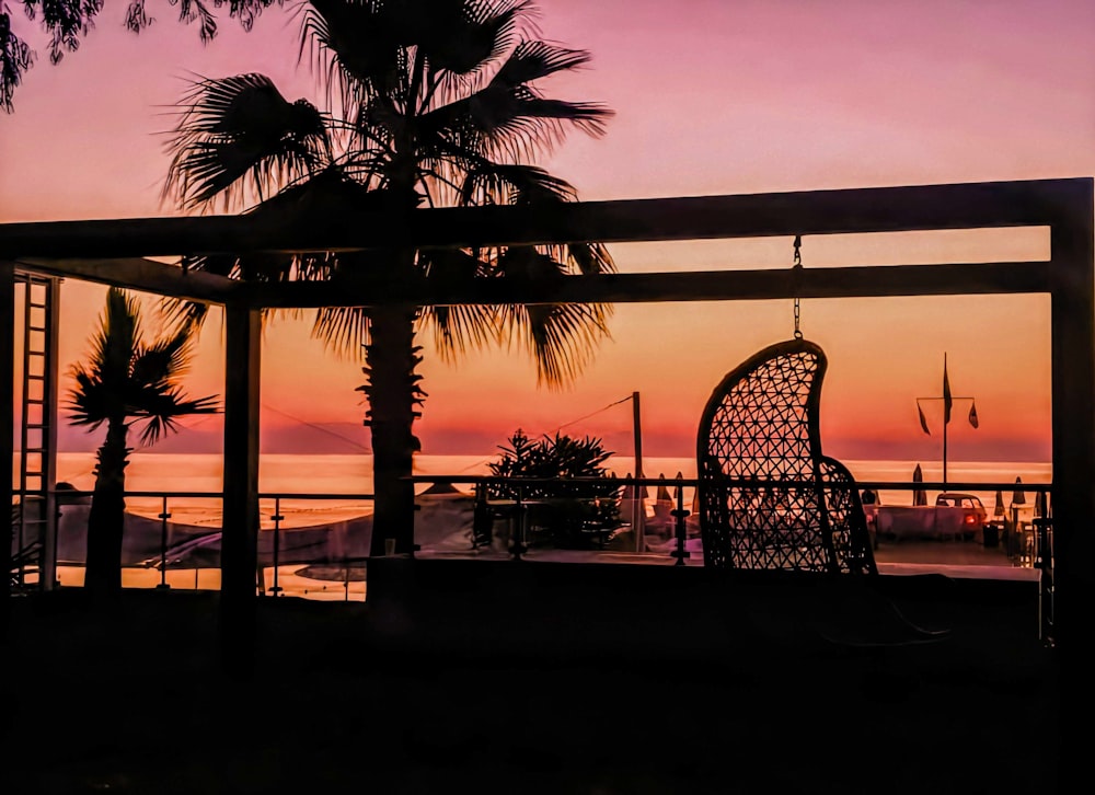 silhouette of palm trees near body of water during sunset