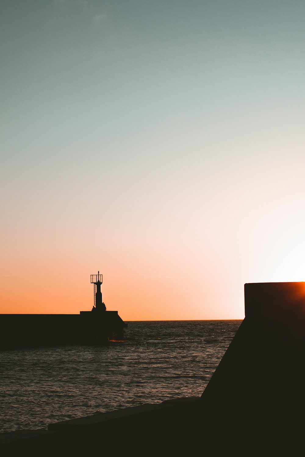 silhouette of a person standing on a dock during sunset