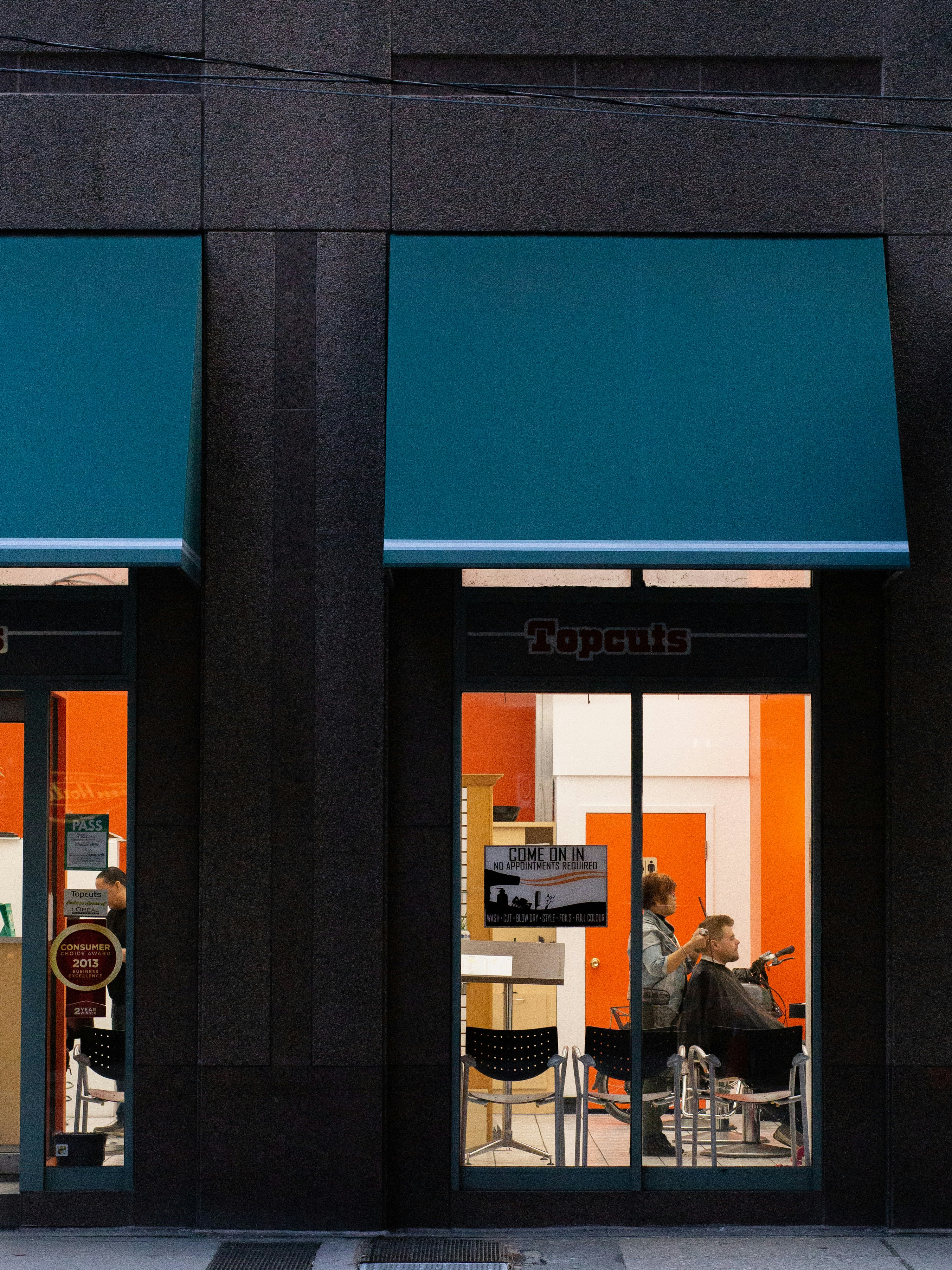 man in black jacket sitting on chair near glass window