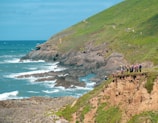 A group engaging in an outdoor coaching seminar on a spacious grassy field with a backdrop of Irish cliffs and sea.