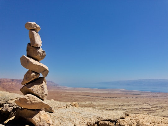 brown rocks on brown sand under blue sky during daytime in Masada National Park Israel
