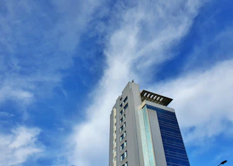A sleek modern luxury condominium building under construction against a clear blue sky.