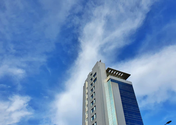A sleek modern luxury condominium building under construction against a clear blue sky.