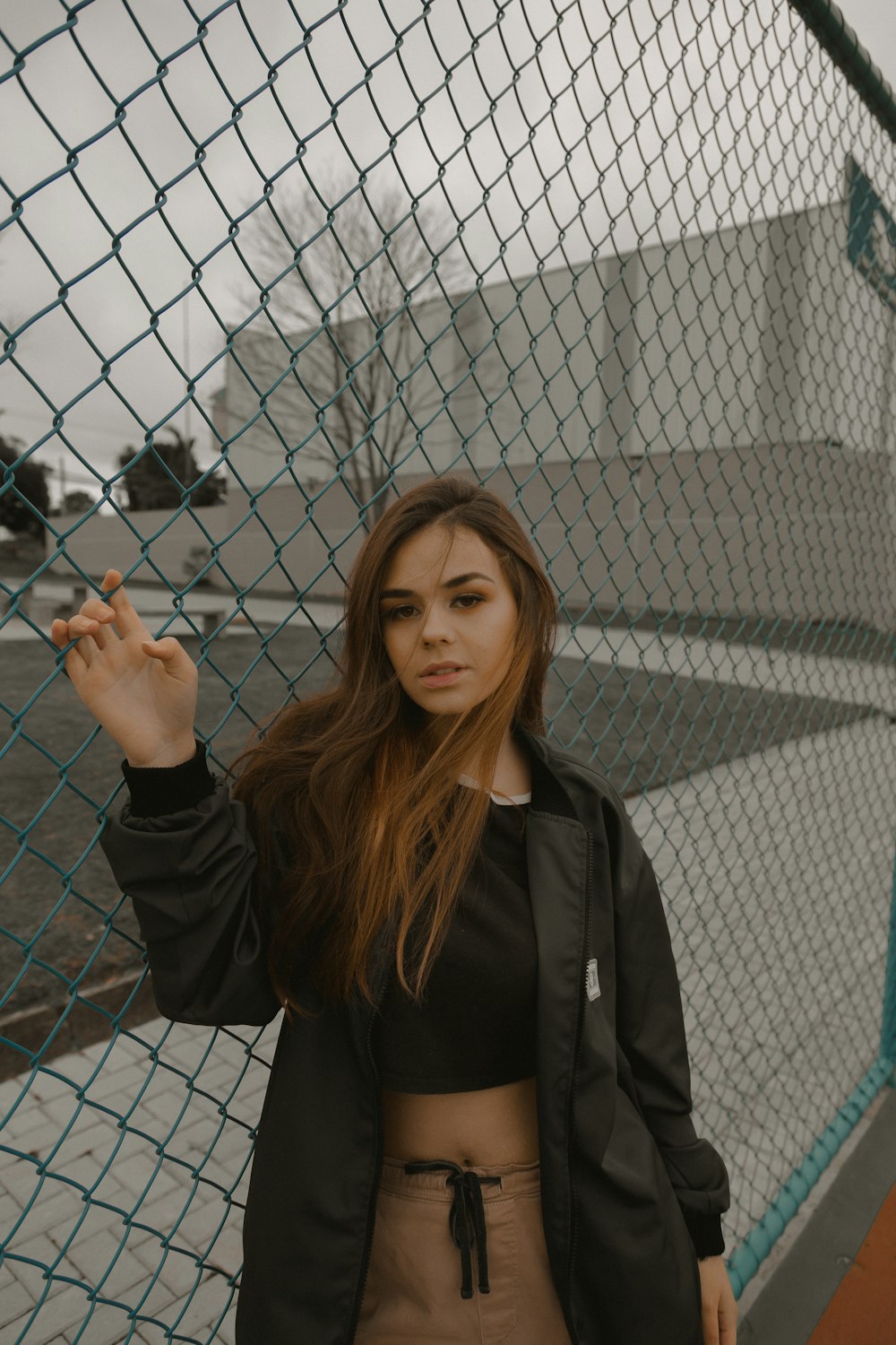 woman in black jacket standing beside gray metal fence