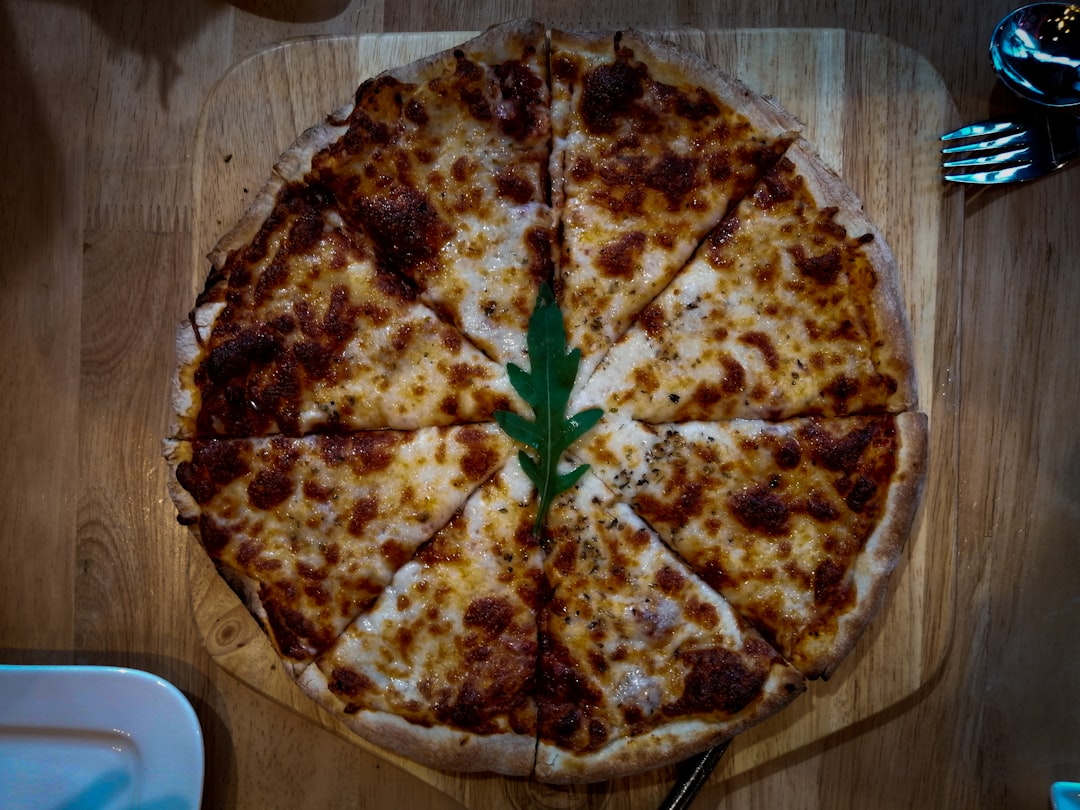 pizza with green leaves on brown wooden table