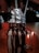 A decadent milkshake topped with whipped cream and chocolate sauce, served in a large glass jar. An Oreo cookie is placed on the side, and two straws extend from the top. The background has a warm, dimly lit ambiance, suggesting a cozy setting.