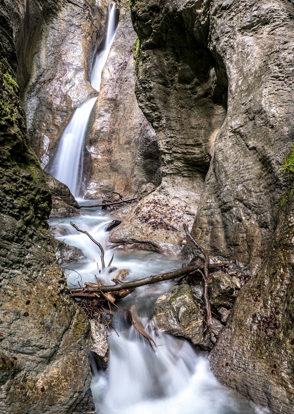 El agua cae entre formaciones rocosas marrones y verdes durante el día