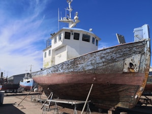 A skilled technician carefully inspecting the hull of a fishing boat docked at the marina under a clear sky