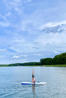 woman in red bikini standing on boat on lake during daytime