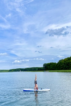 woman in red bikini standing on boat on lake during daytime