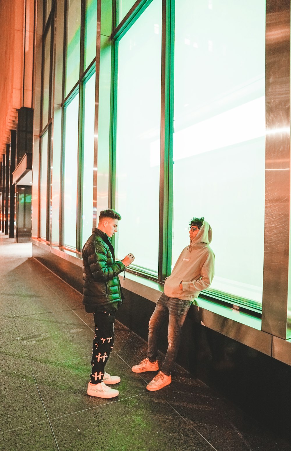 man in green jacket and black pants standing beside woman in green jacket