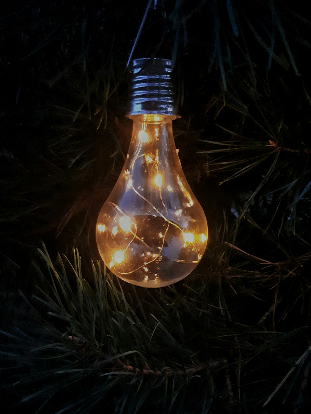 a light bulb hanging from a christmas tree