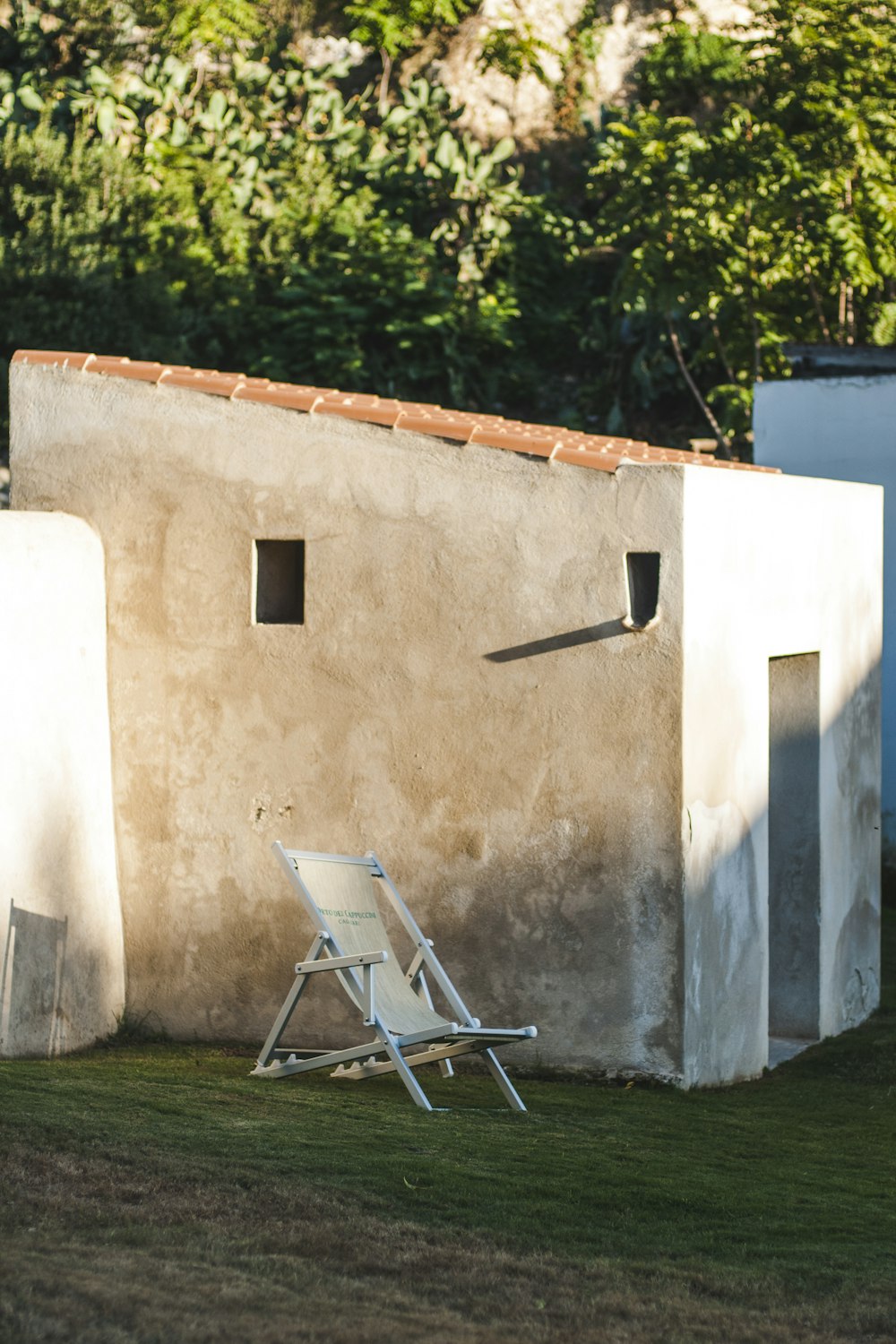 white and black folding chair beside white wall