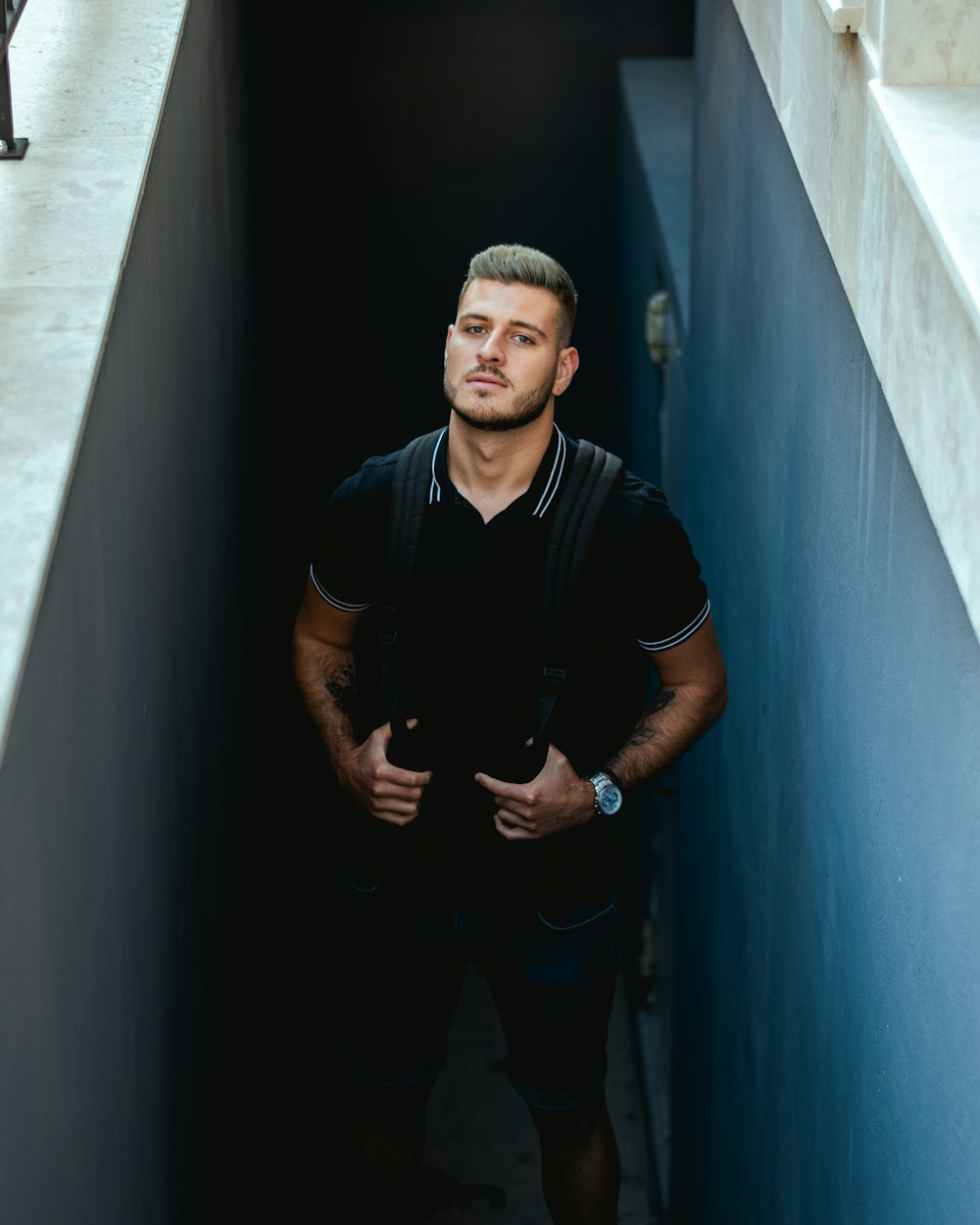 man in black polo shirt standing beside wall