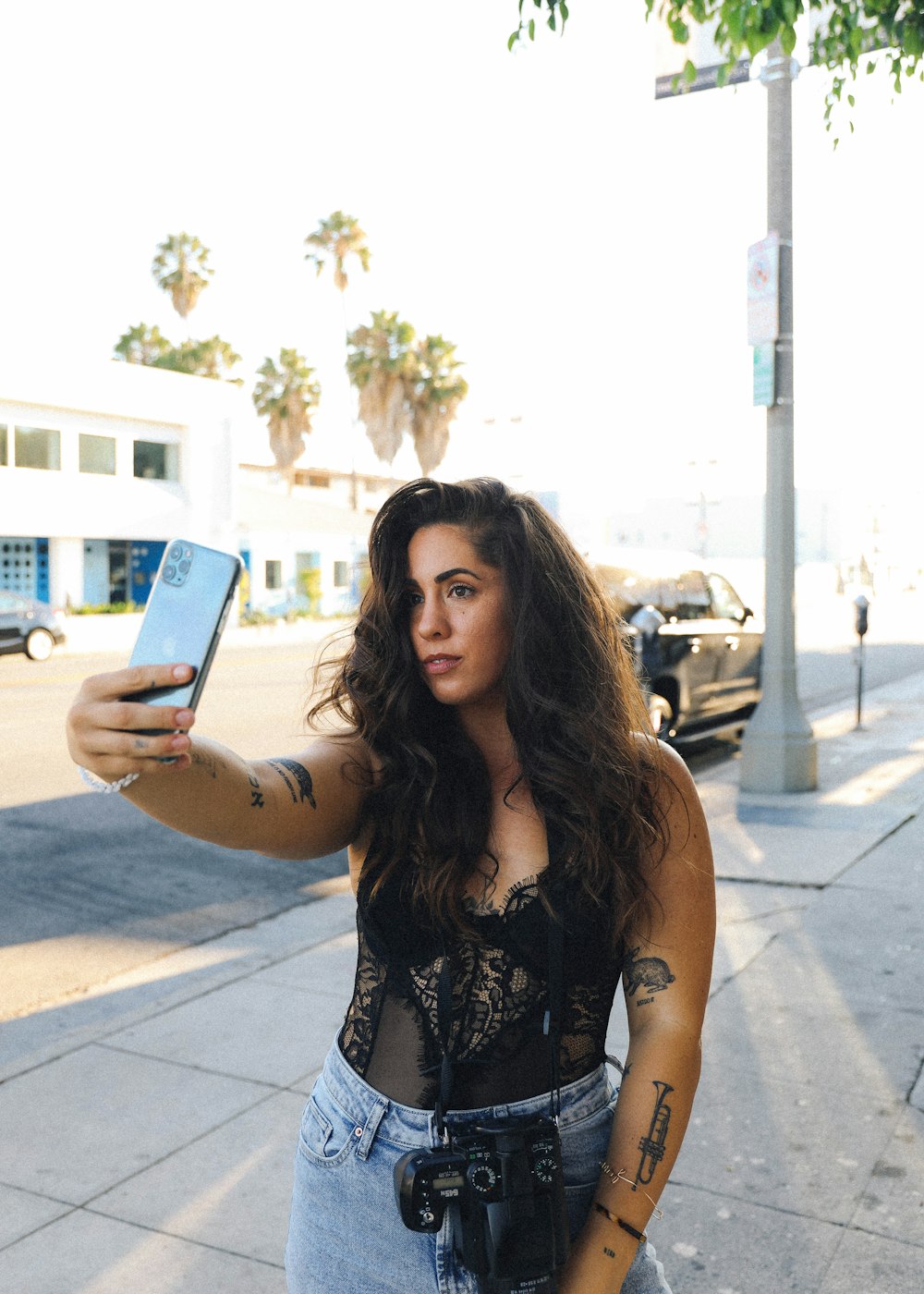 woman in black and white floral sleeveless top holding blue smartphone