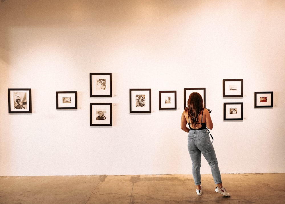 woman in blue denim jeans standing in front of white wall with 3 black wooden picture