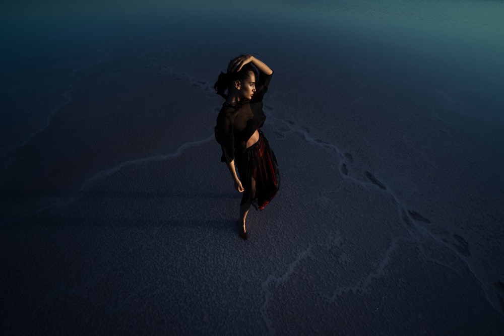 woman in black dress running on sand during daytime