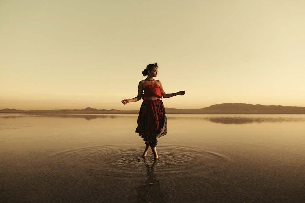 woman in red dress standing on beach during sunset