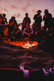 Teenagers gathered outdoors around a campfire, sharing stories and laughter.