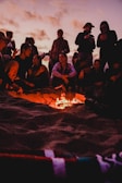 Students gathered around a fire sharing stories under a twilight sky.