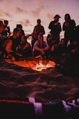 Teenagers gathered outdoors around a campfire, sharing stories and laughter.