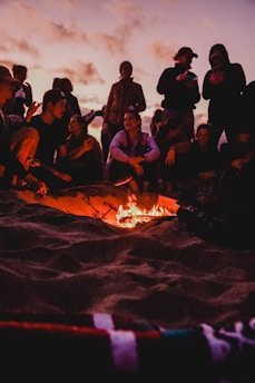 A group of men gathered around a campfire on the Baltic Sea coast, sharing stories and laughter at sunset.