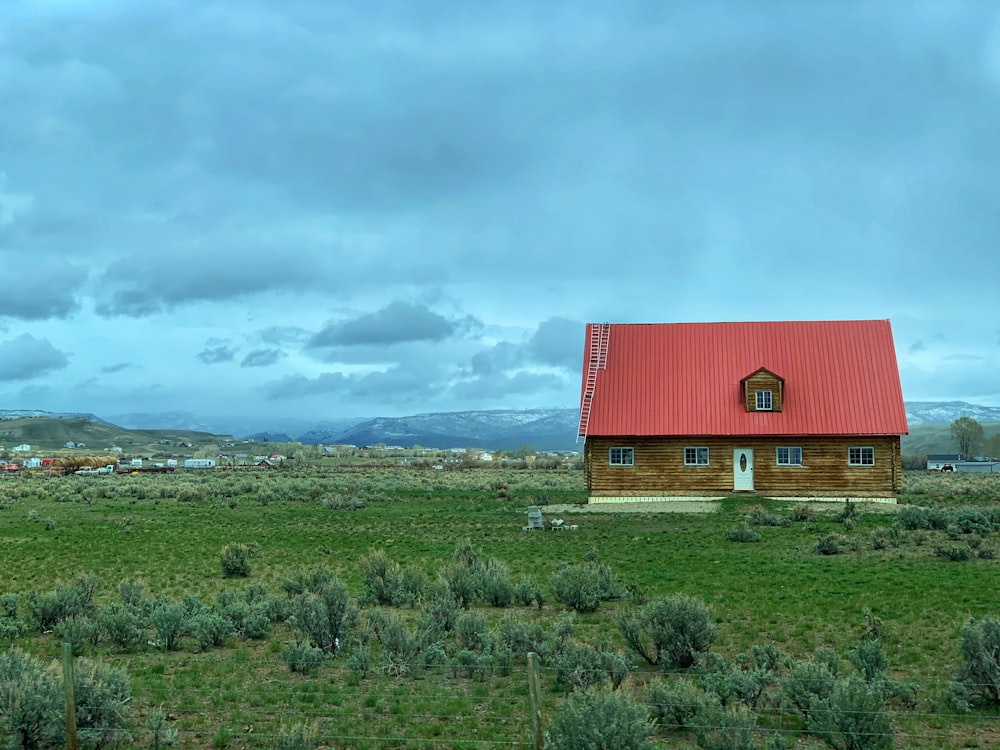 red barn on green grass field under white clouds during daytime