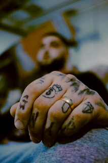 Close-up of a hand tattoo featuring delicate script and small symbols.