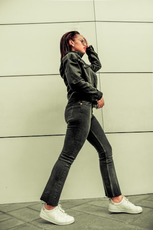 A model walking confidently wearing denim and a casual shirt.