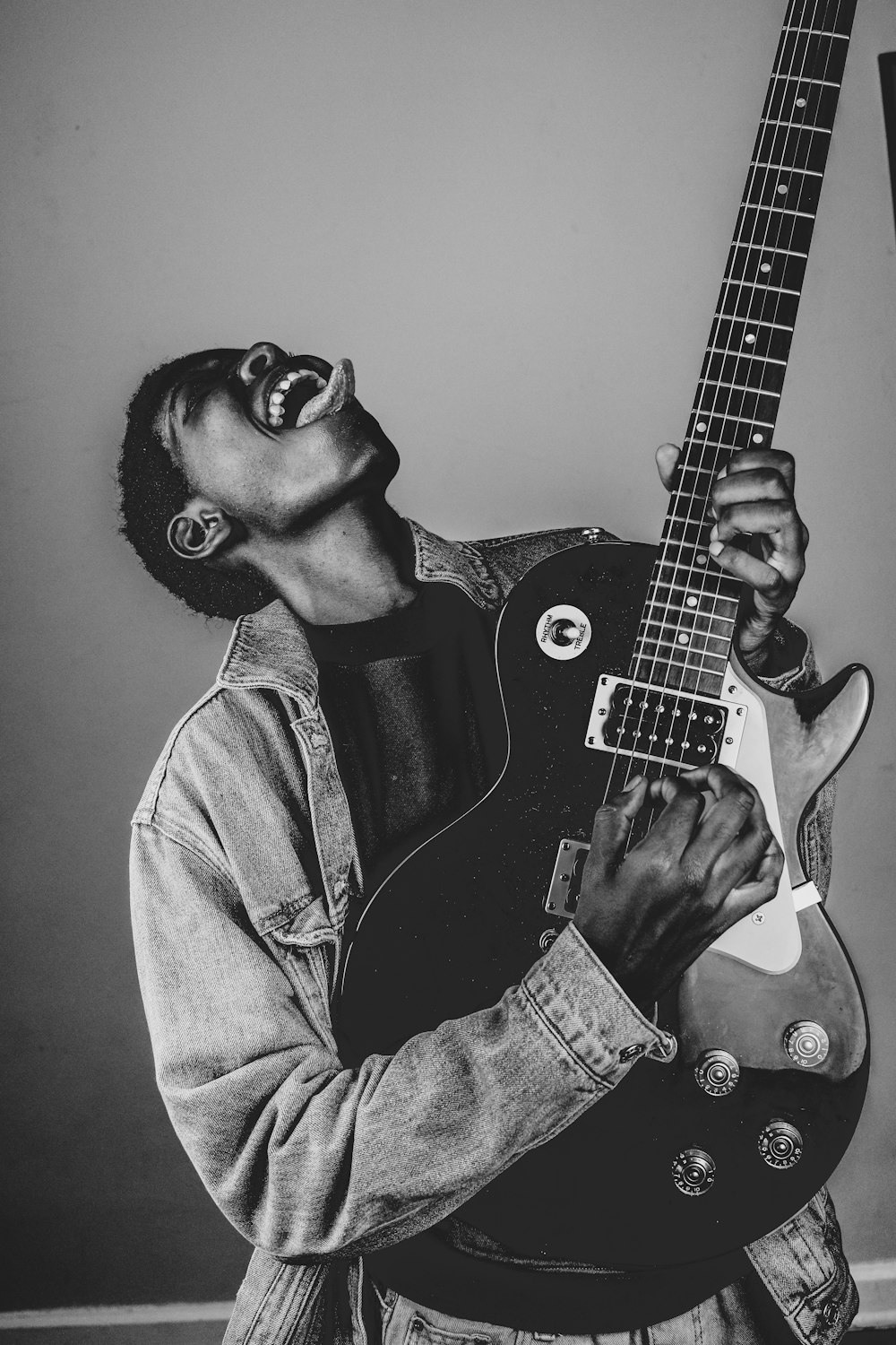 man in denim jacket playing electric guitar