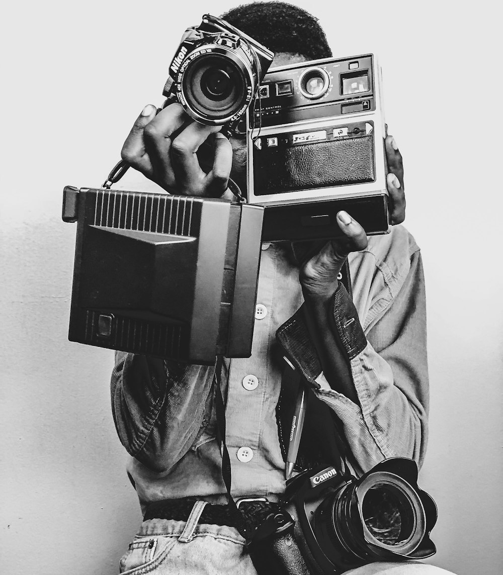 Foto in scala di grigi di un uomo che tiene la macchina fotografica