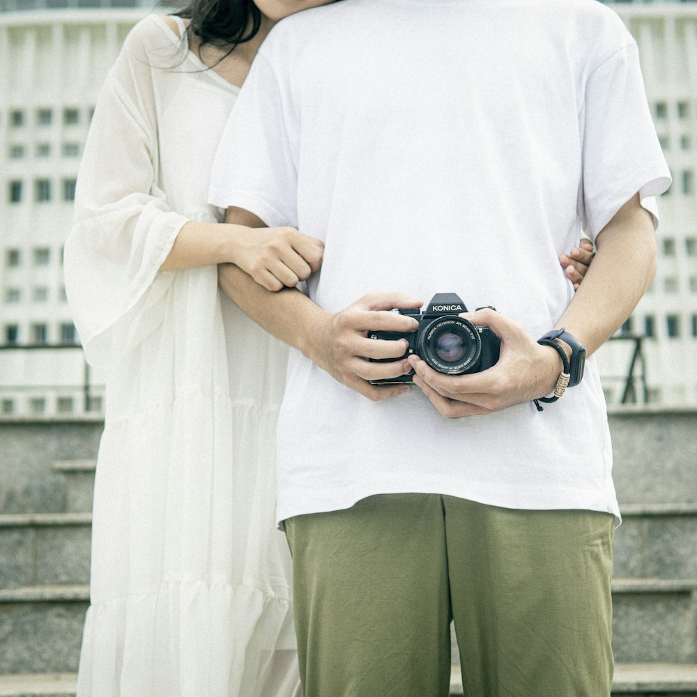 woman in white t-shirt and green pants holding black dslr camera