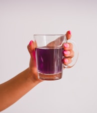 person holding clear glass mug with brown liquid
