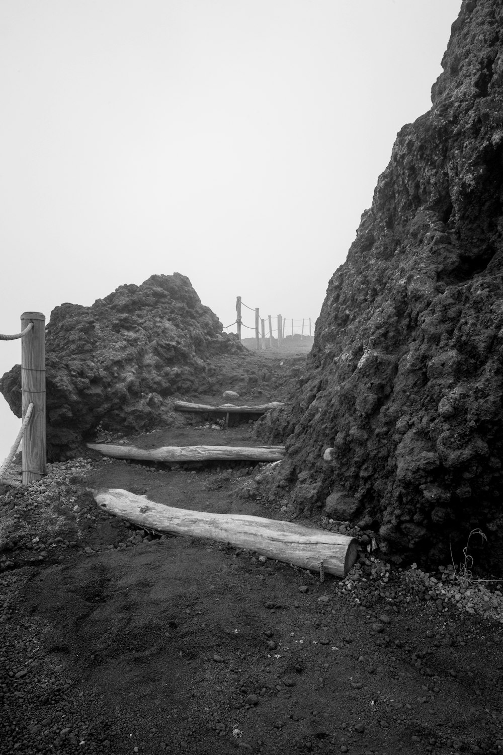 grayscale photo of wooden fence on mountain