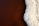 Aerial view of a contrast between a smooth, brown surface and a rough, white textured substance on the right. The white area appears to be crystalline or salt-like in texture.