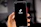 An anonymous figure recording a TikTok video with a smartphone, background blurred for privacy.