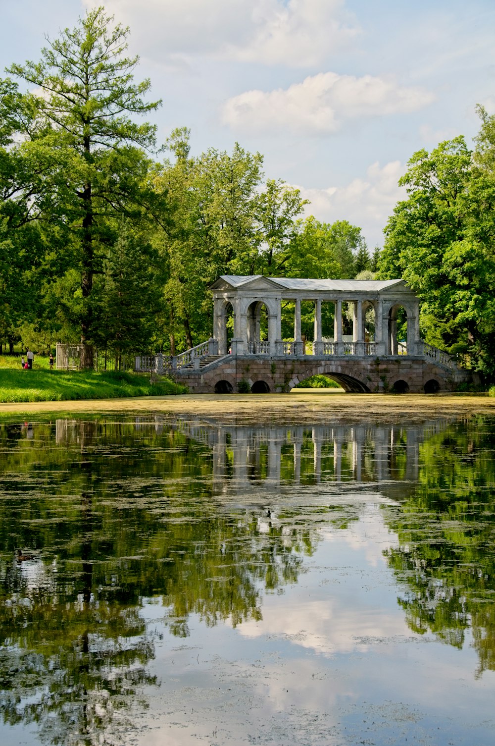 white concrete building near green trees and river during daytime