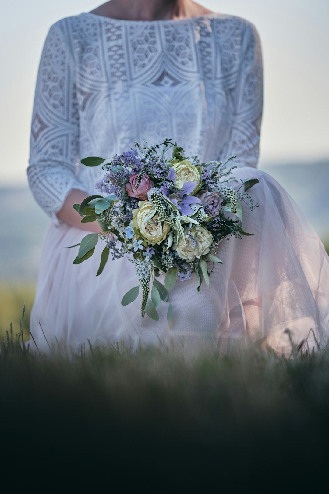 woman in white floral dress holding bouquet of flowers