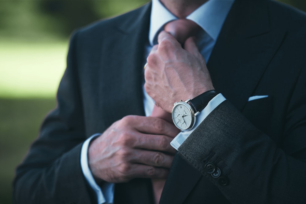 man in black suit jacket wearing silver round analog watch