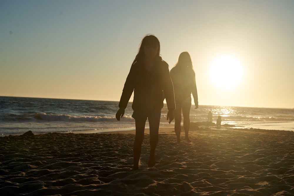 silhouette of 2 person standing on beach during sunset