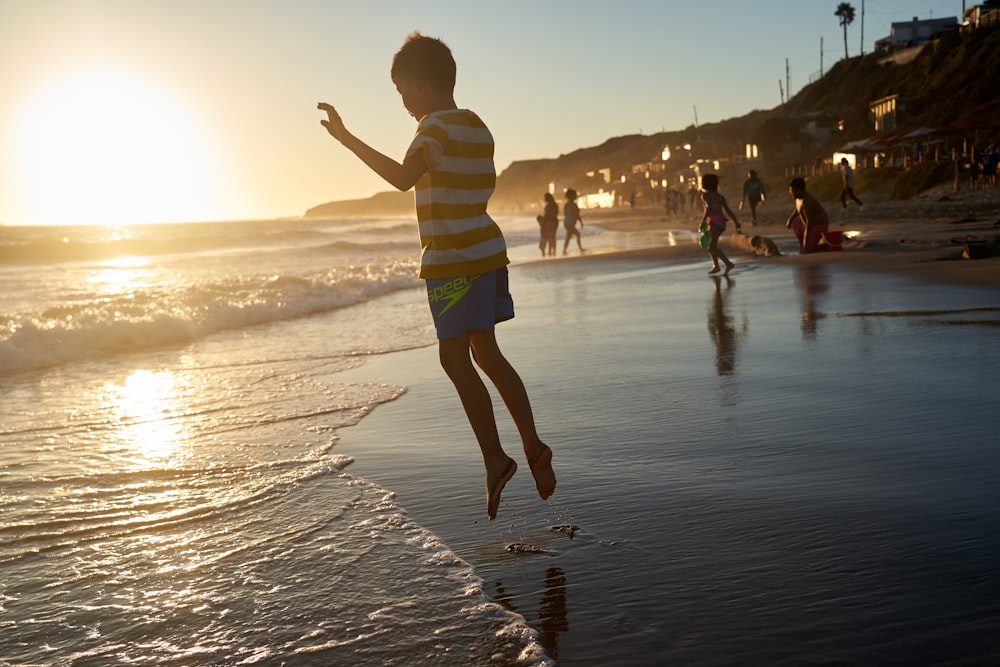 boy in green and white stripe shirt standing on beach during daytime